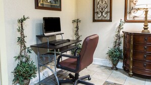 Um espaço de escritório em casa com escrivaninha, cadeira, computador e plantas decorativas.