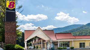 Um motel Super 8 com entrada em tijolos, telhado vermelho e montanhas ao fundo.
