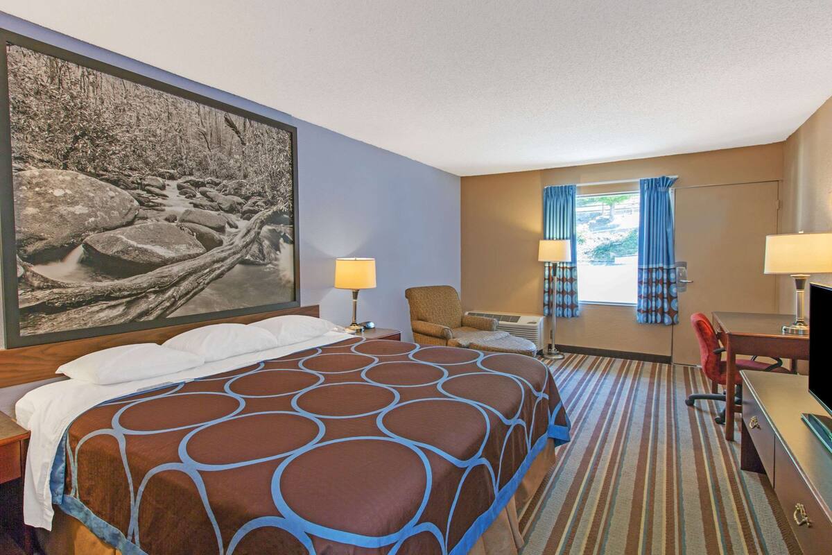 Une chambre d’hôtel avec un grand lit, un bureau, une chaise et un téléviseur.