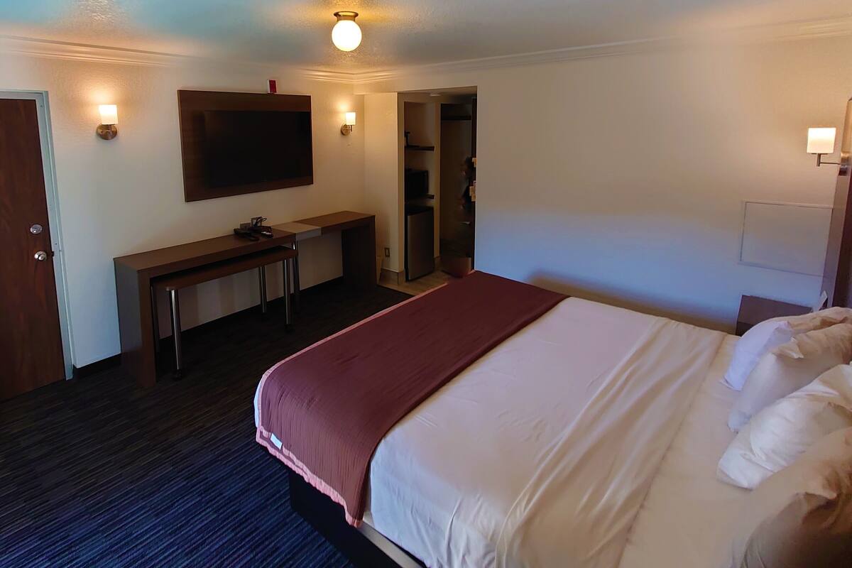 Une chambre d’hôtel équipée d’un lit, d’un bureau, d’une télévision et d’une armoire.