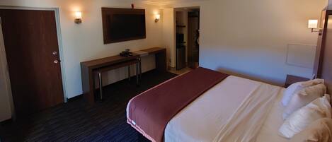 Una habitación de hotel con cama, escritorio, televisión y armario.