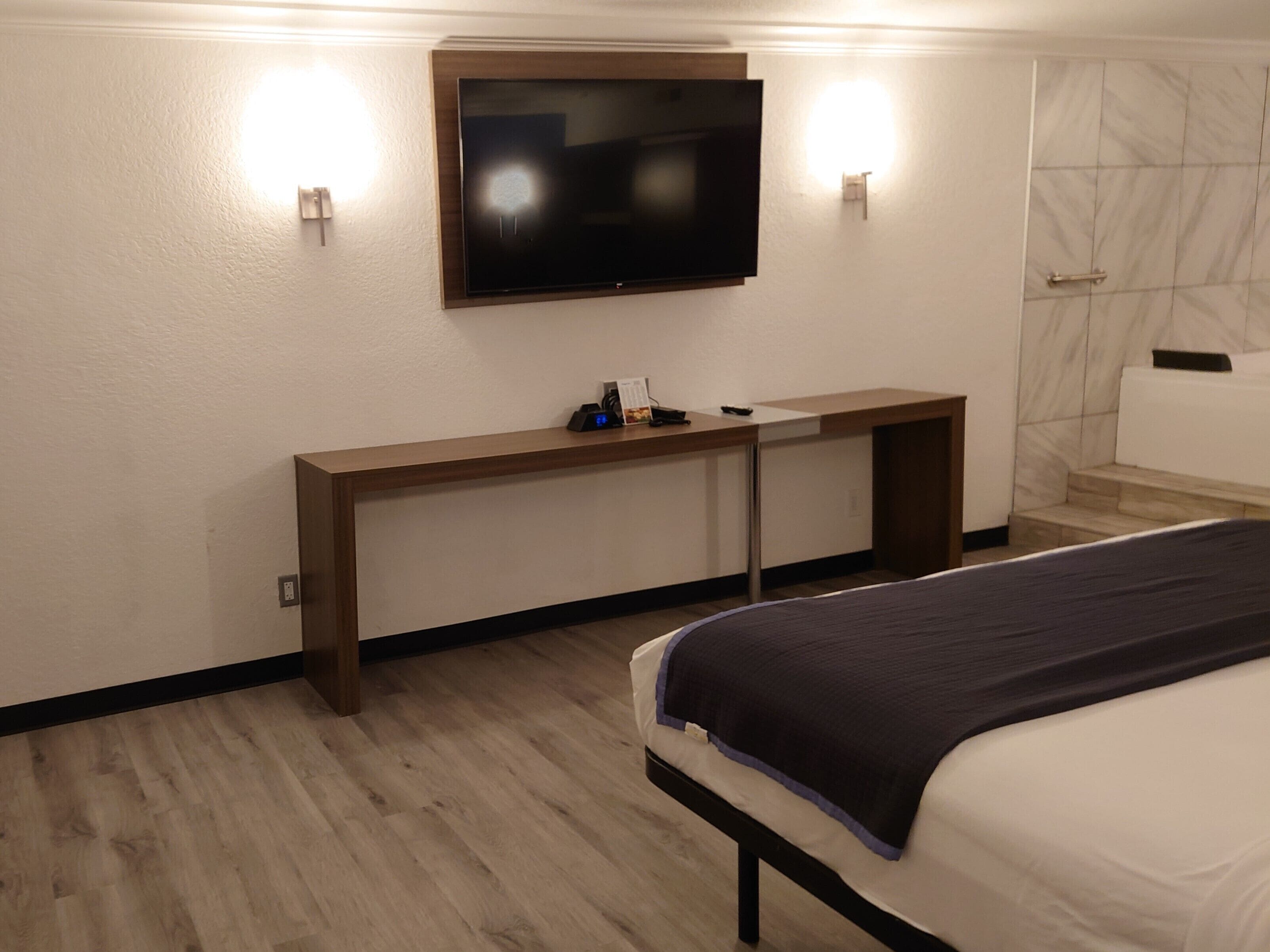 Een hotelkamer met een bed, een bureau met een flatscreen televisie, en een badkamer met een marmeren wand.