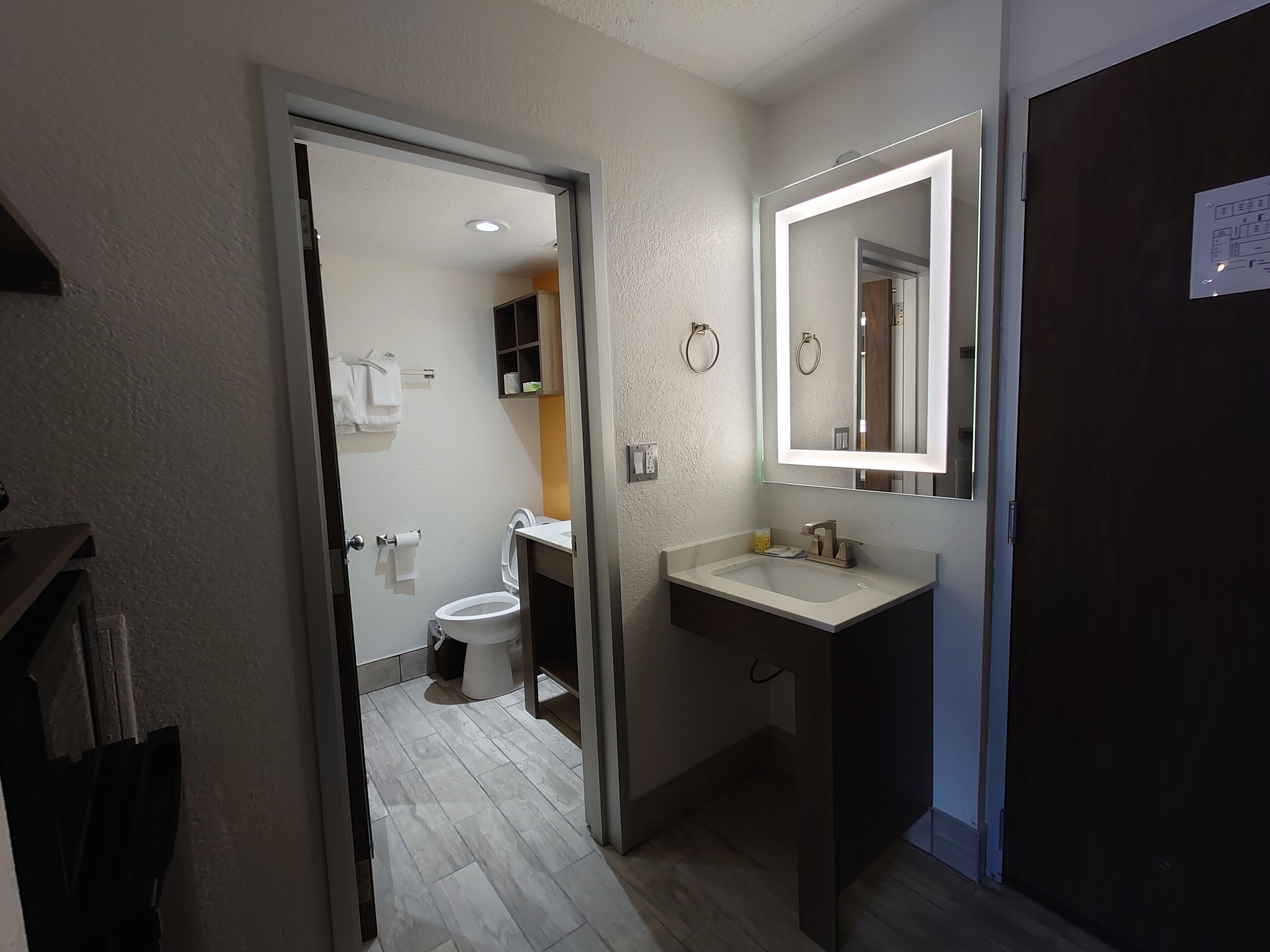 A modern bathroom with a white sink, mirror, and toilet.