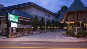 A hotel entrance with a sign for Reagan Resorts Inn, a stone wall, and a landscaped area with a fountain. - Reagan Resorts Inn (Gatlinburg)