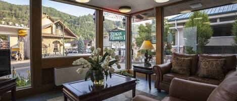 Un hall de hotel con un amplio ventanal que ofrece vistas a una montaña y un cartel de Reagan Resorts.