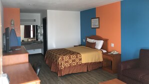 Une chambre d’hôtel comprenant un lit, un bureau, une chaise, une télévision, une salle de bain avec douche et un miroir.