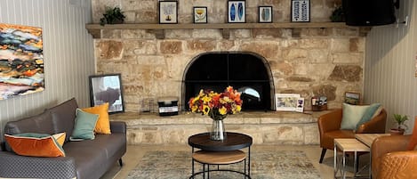 Una sala de estar con chimenea de piedra, un sofá, una mesa de centro y un televisor montado en la pared.