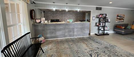 A reception area with a counter, a bench, a rug, and a sofa.