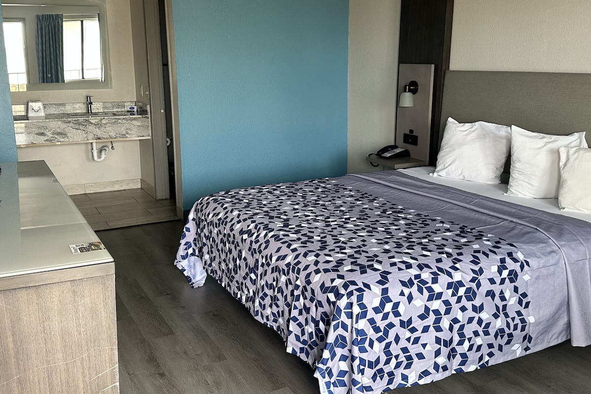 Habitación de hotel con cama, baño y una pequeña kitchenette.
