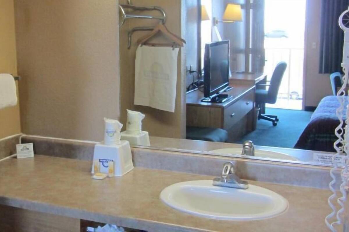 Un baño de hotel con lavamanos, espejo, toallero y artículos de aseo.