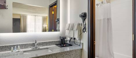 Baño con encimera de granito, secador de pelo, toallero y cortina de ducha.