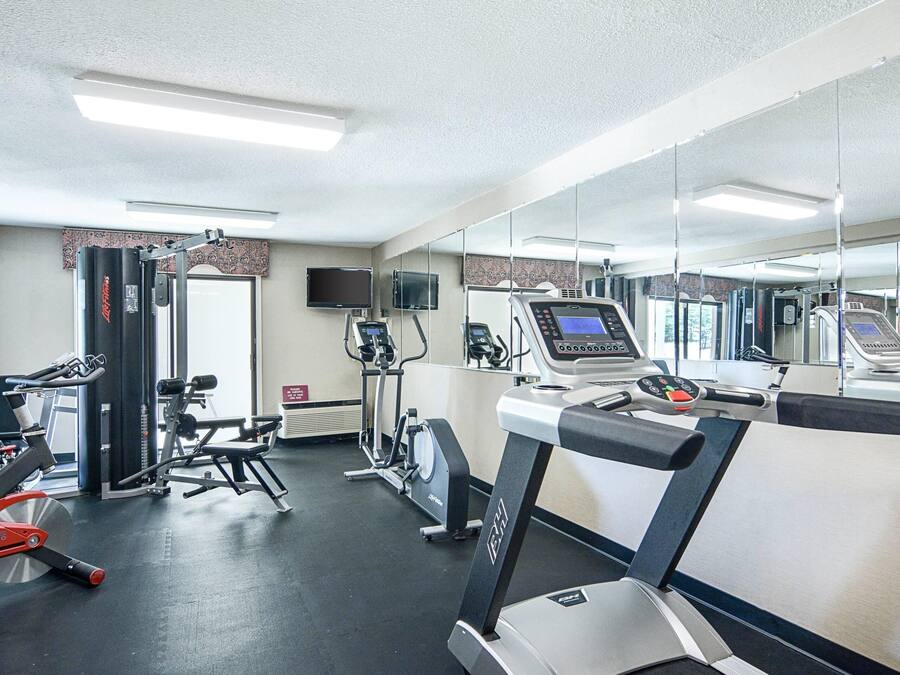 A gym with cardio equipment, weight machines, and a mirrored wall.