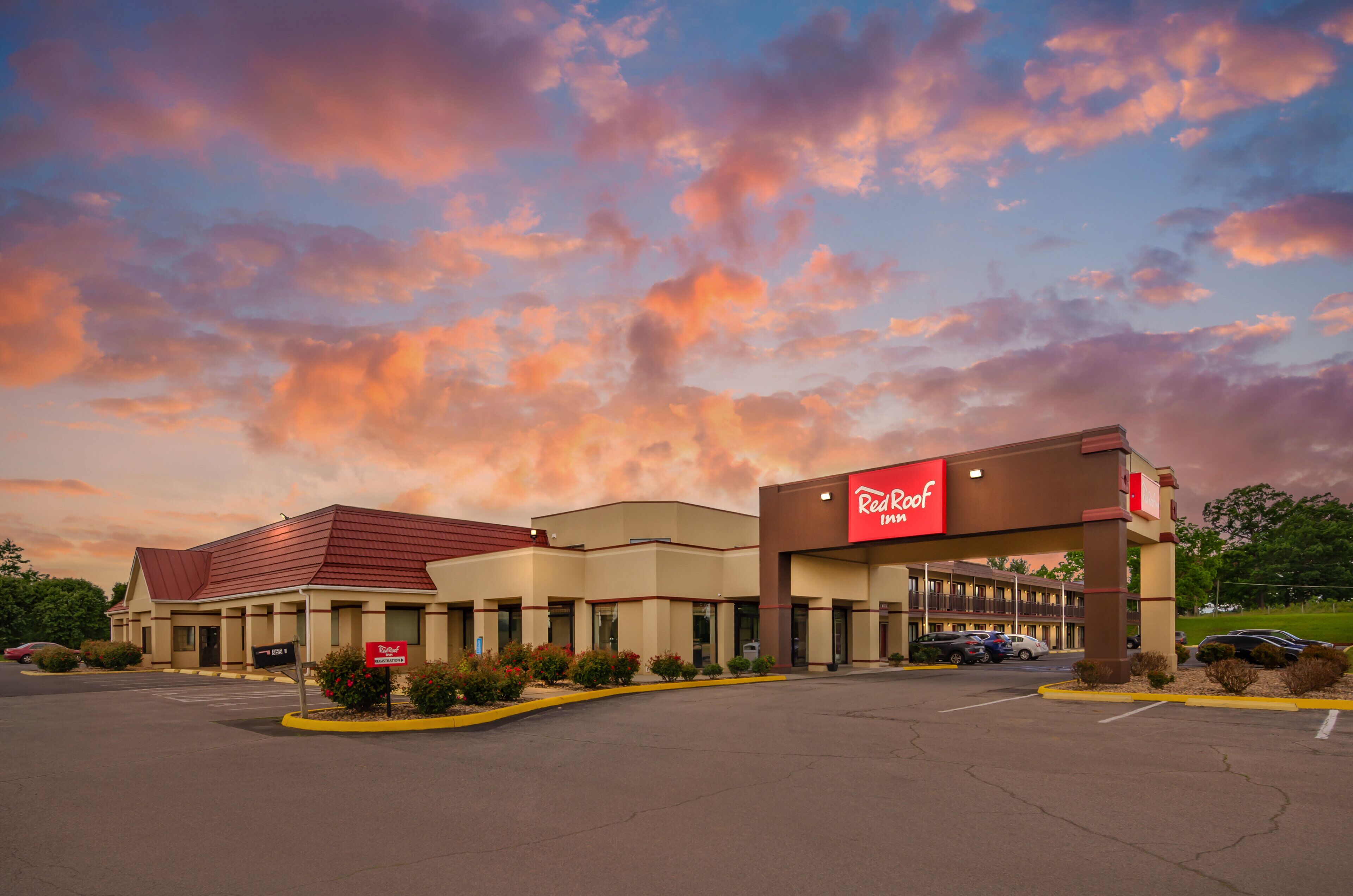 Um Red Roof Inn com telhado vermelho, paredes bege e estacionamento.