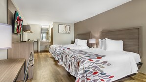 A hotel room with a long bed, a desk, a TV, and a bathroom visible through an open door. - Red Roof Inn Staunton (Staunton)