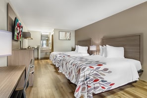 A hotel room with a long bed, a desk, a TV, and a bathroom visible through an open door. - Red Roof Inn Staunton (Staunton)