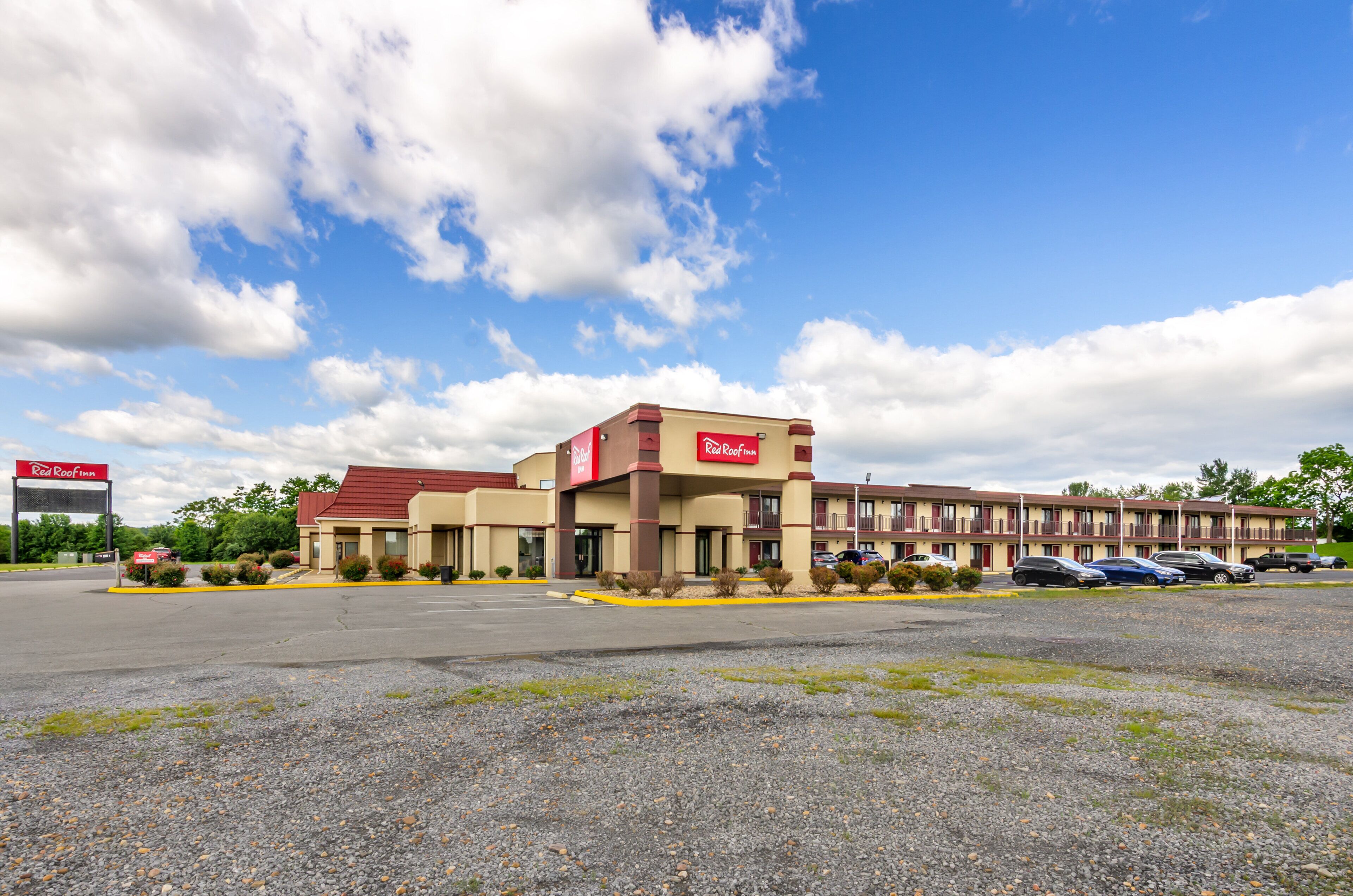A Red Roof Inn with a parking lot and a clear sky.