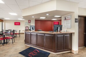 A hotel reception area with a counter, chairs, and a sign indicating free Wi-Fi in all rooms.