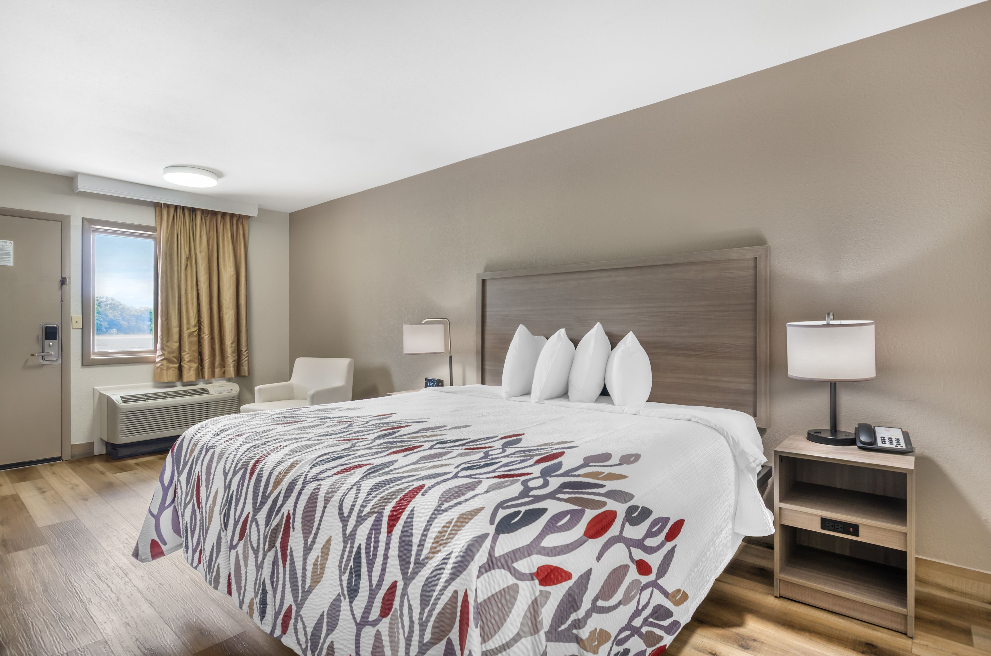 Habitación de hotel con una cama grande, dos mesitas de noche con lámparas, una ventana con cortinas y vistas a las montañas.