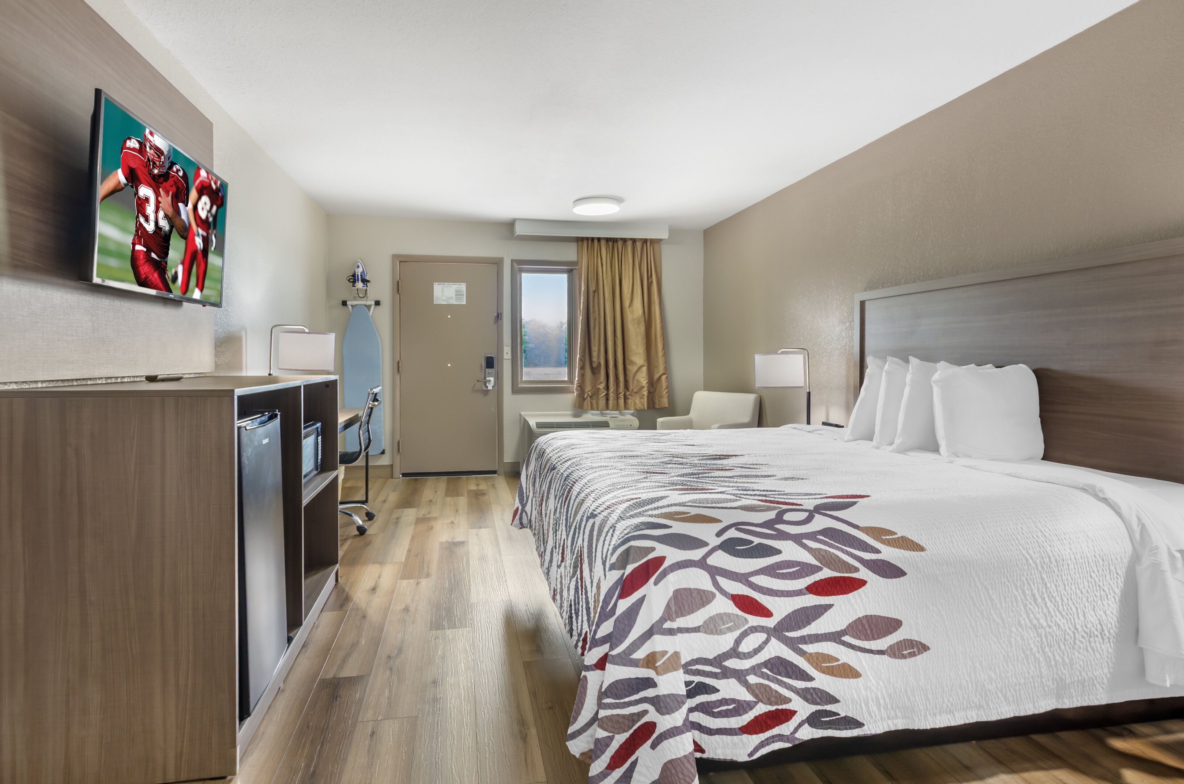 Una habitación de hotel con cama, escritorio, televisor y armario.