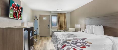 Una habitación de hotel con cama, escritorio, televisor y armario.