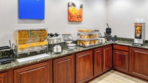 A breakfast buffet with various food items, a waffle maker, and a coffee machine. - Comfort Inn Monticello (Charlottesville)