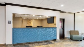 A reception area with a blue counter, a flat-screen TV mounted on the wall, and a sign indicating room number 25. - Comfort Inn Monticello (Charlottesville)