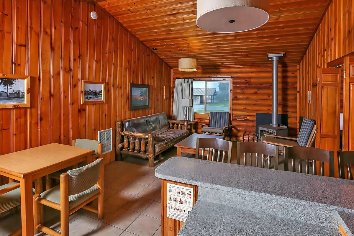 L’intérieur chaleureux d’un chalet avec des murs en bois, un coin repas, un canapé et une cheminée.