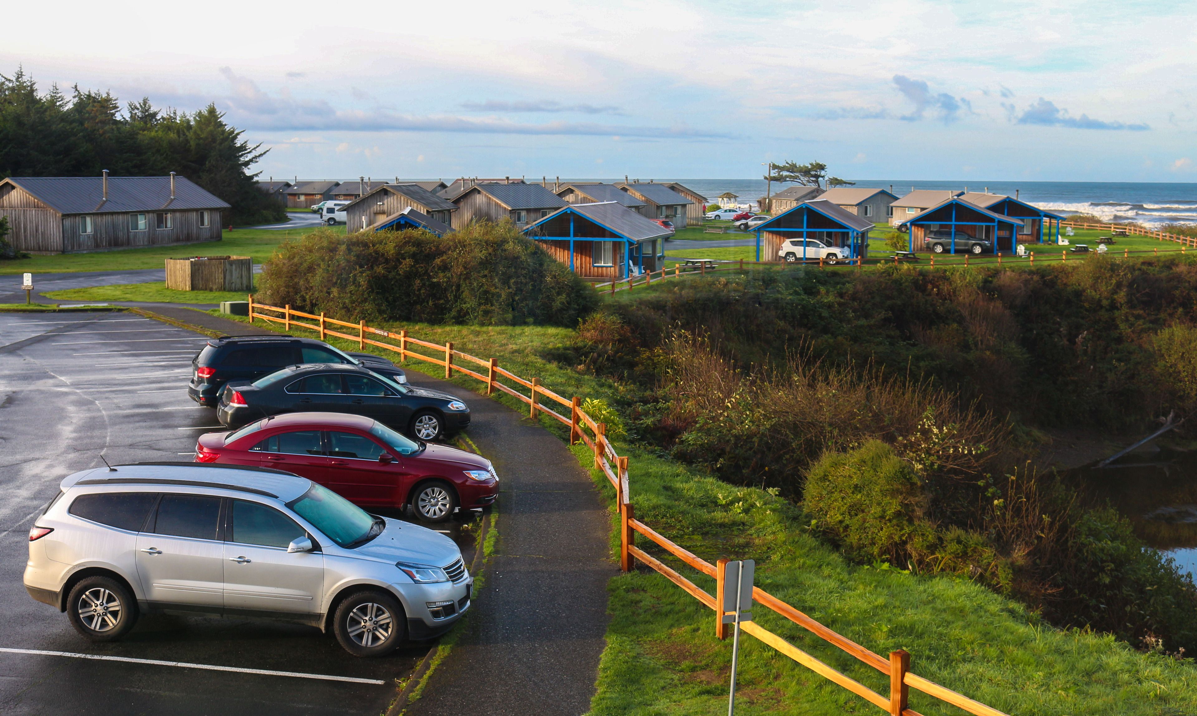 A coastal area with wooden cabins and a parking lot.