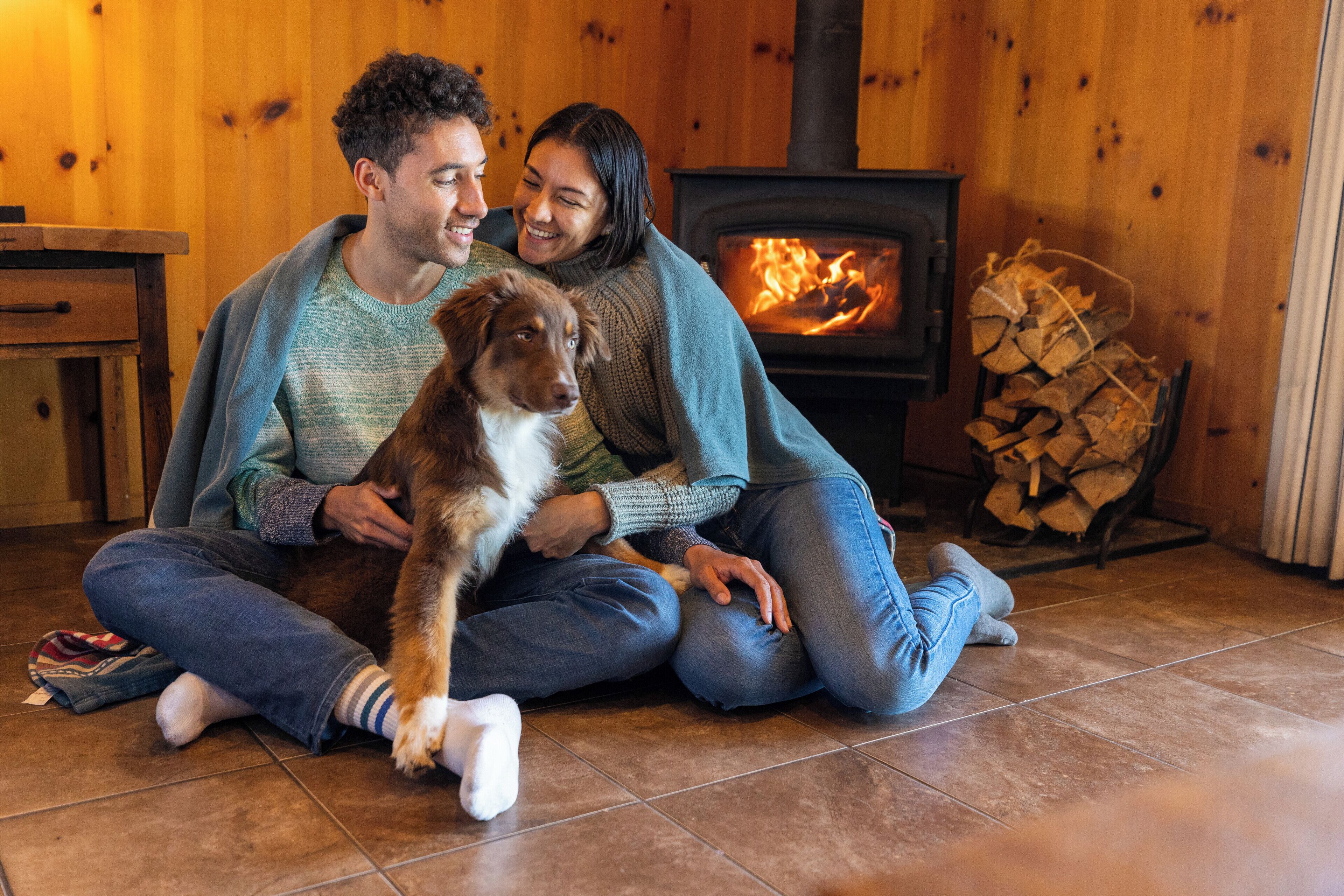 A couple sitting on the floor in a wooden room with a fireplace.