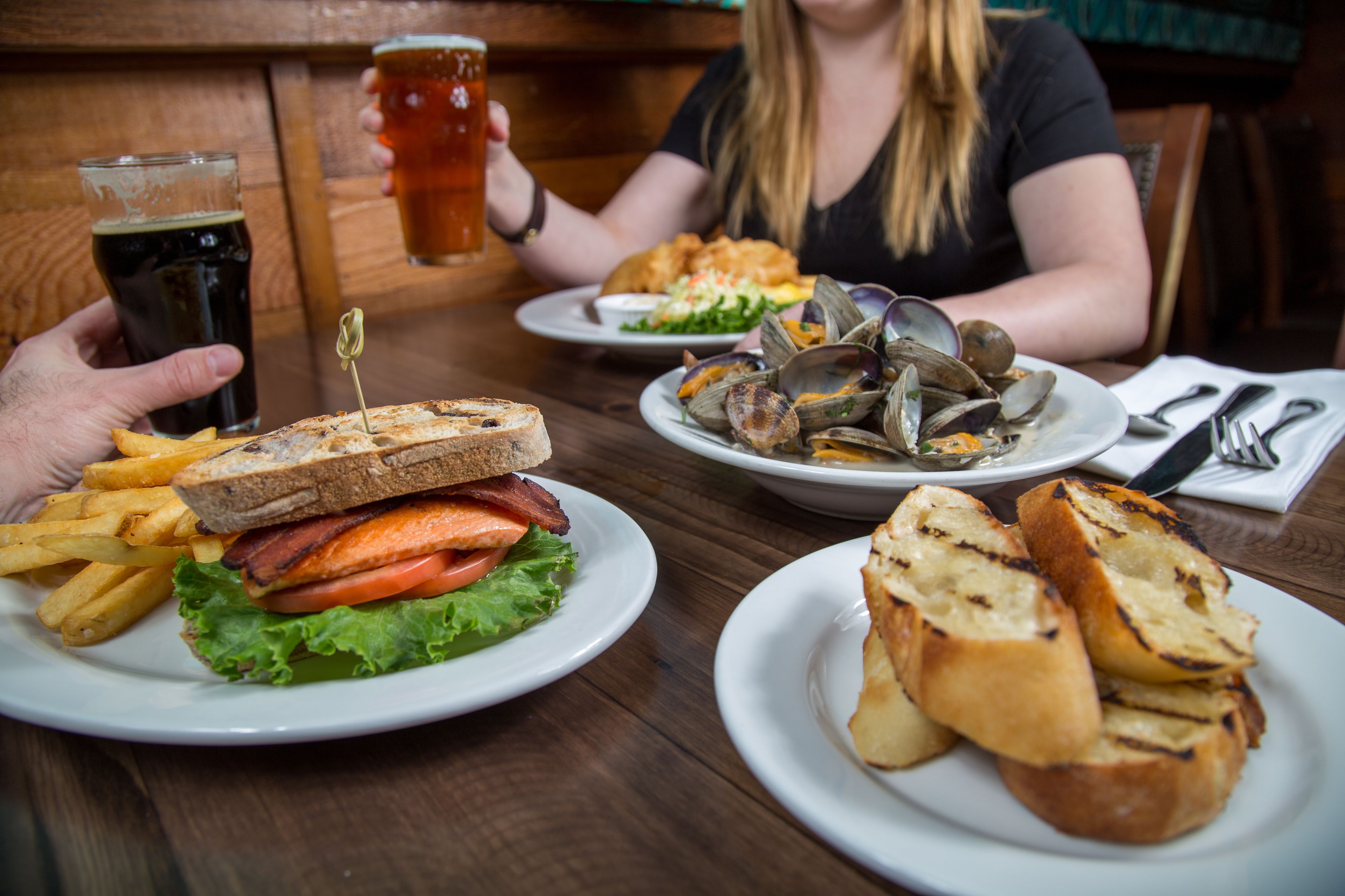 A dining table with plates of food, including a sandwich, fries, and clams.