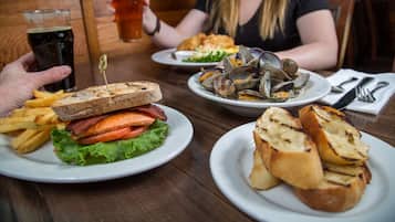 A dining table with plates of food, including a sandwich, fries, and clams.