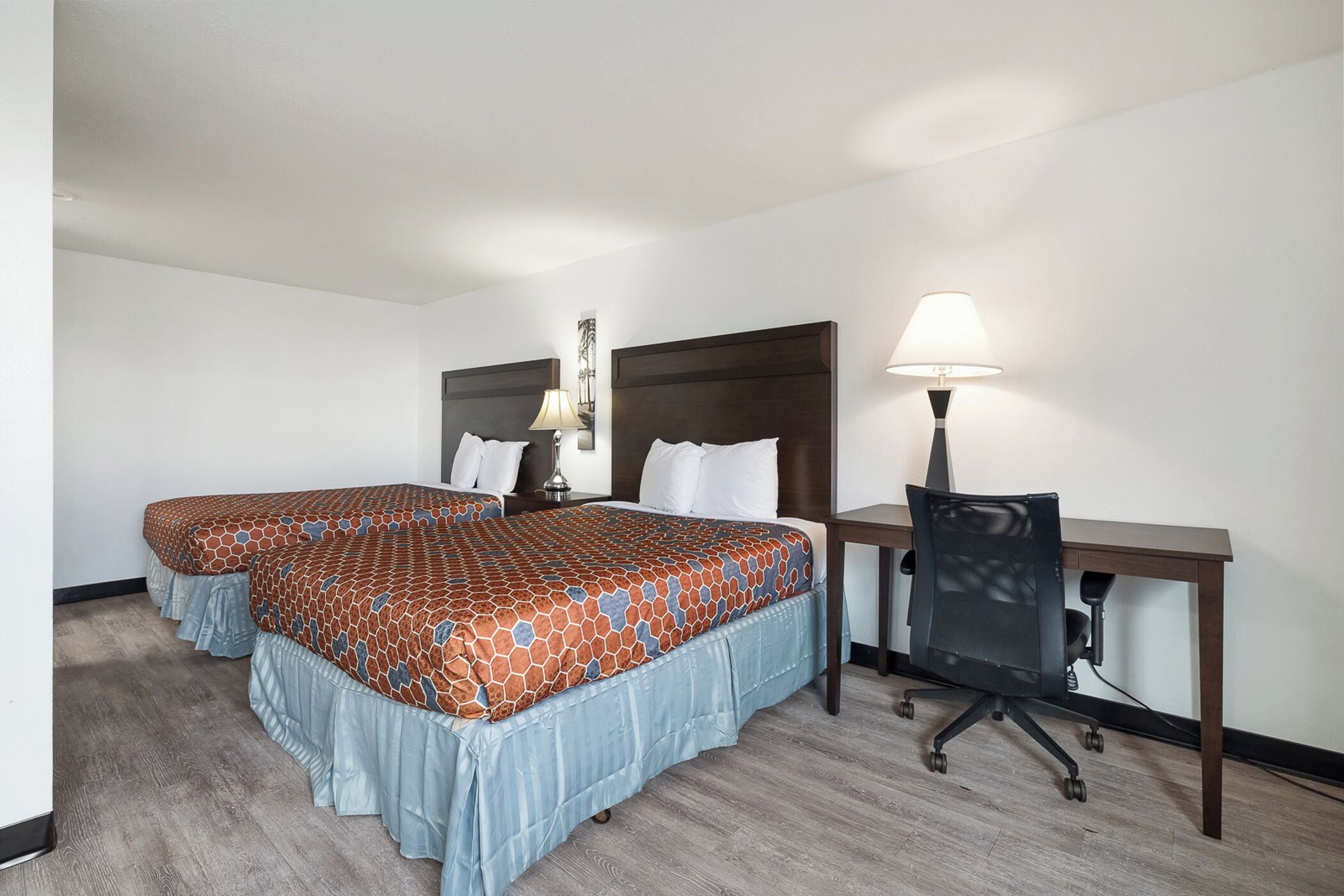Una habitación de hotel con dos camas, un escritorio y una silla.