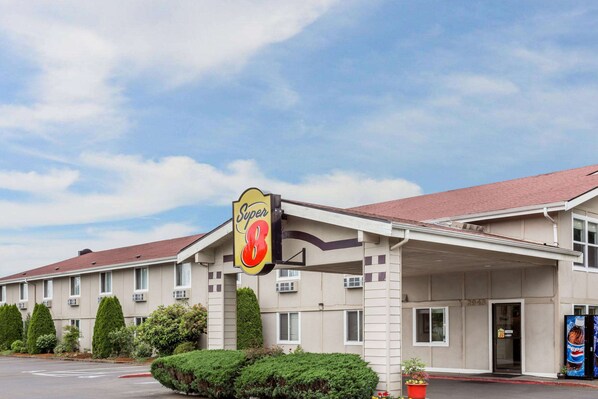 A motel with a 'Super 8' sign, a covered parking area, and a red curb. - Super 8 by Wyndham Shelton (Shelton)