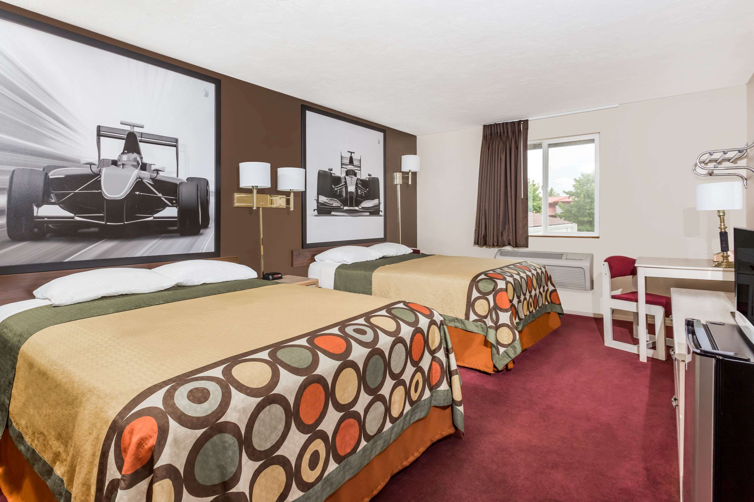 Una camera d'albergo con due letti, una scrivania, una sedia e una televisione.
