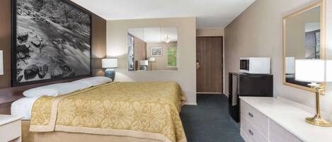 A hotel room with a bed, a desk, a dresser, a mirror, a lamp, and a large framed picture on the wall.