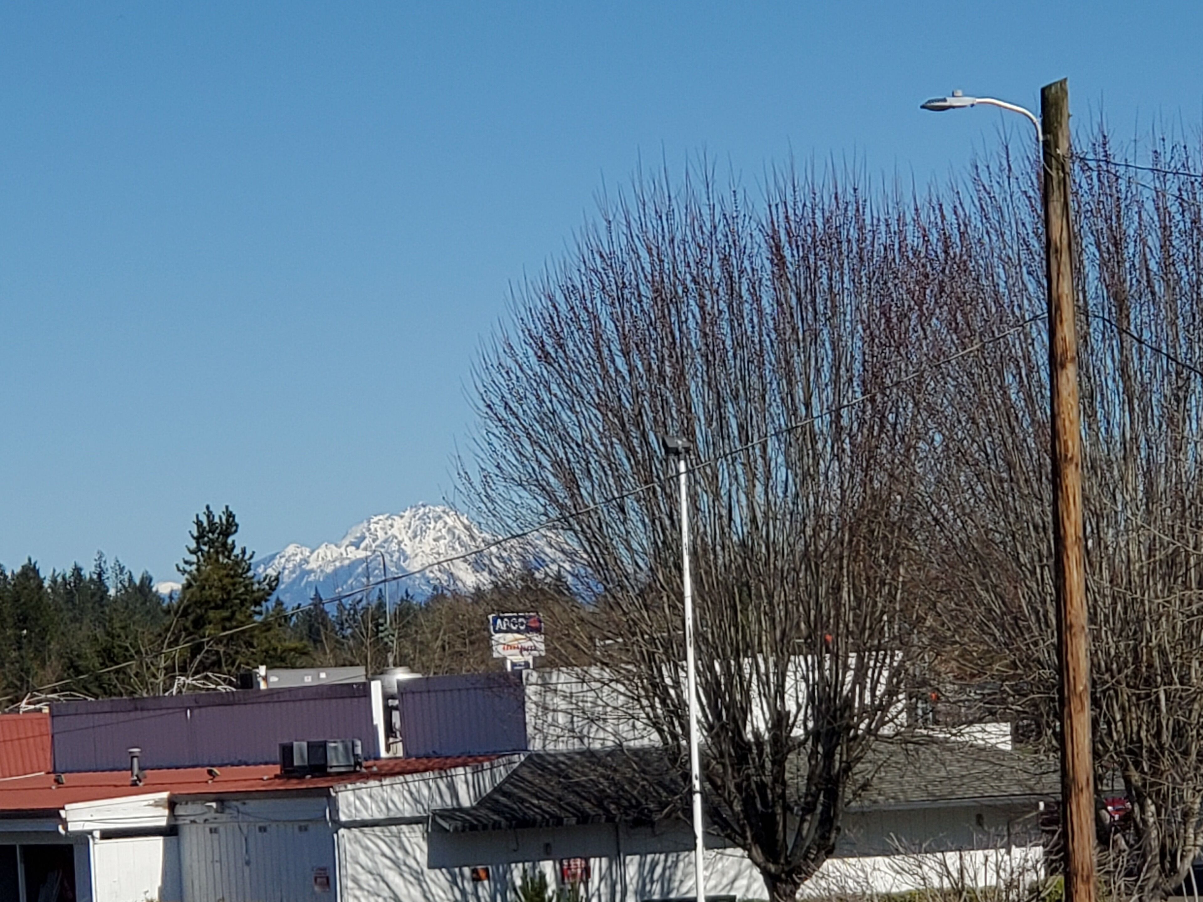 A building with a red roof, a street lamp, and a mountain in the background.