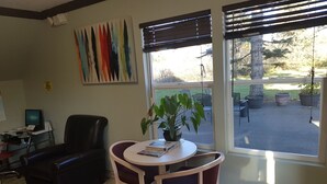 Una habitación con escritorio, computadora, silla y una mesa con una planta.