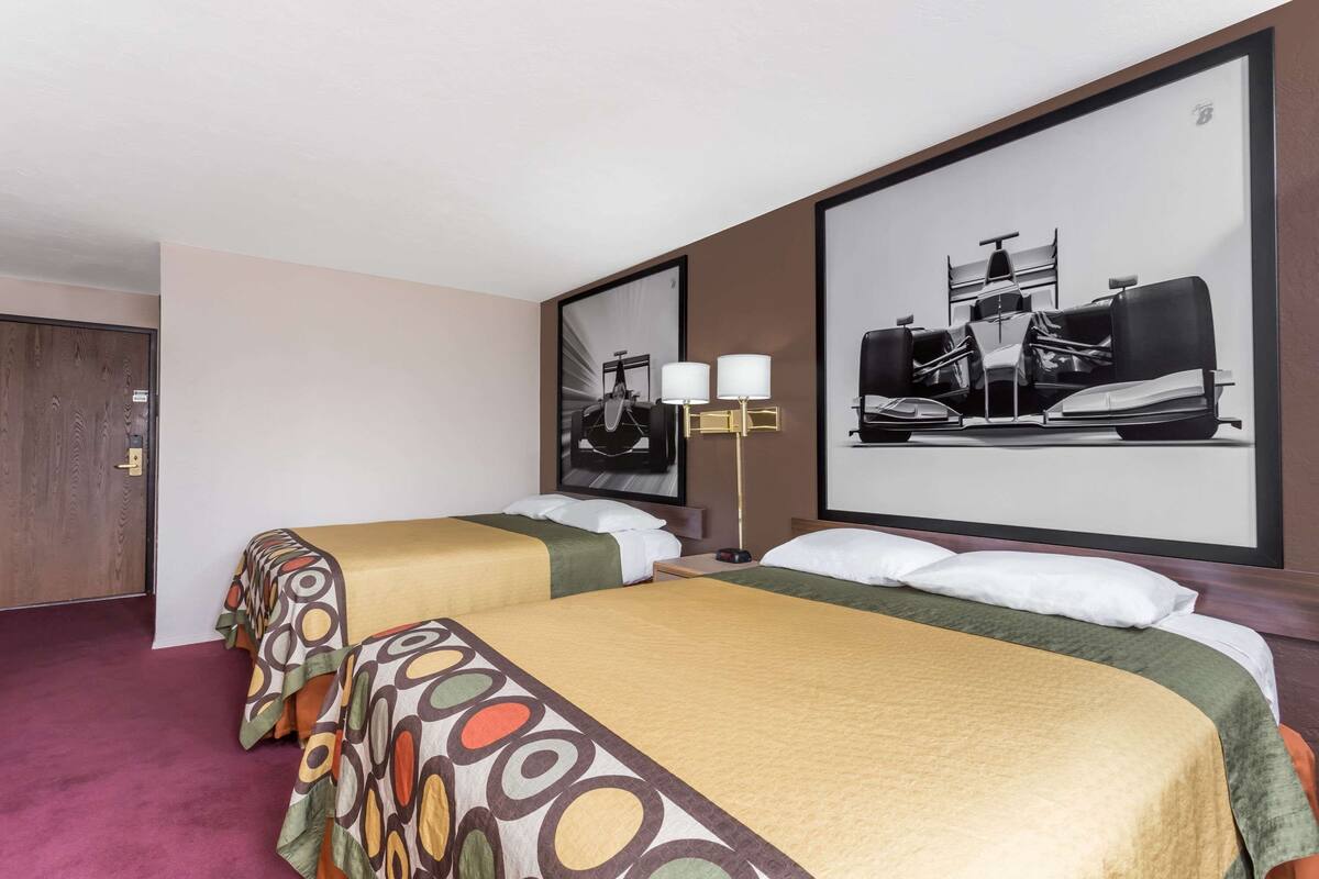 Ein Hotelzimmer mit zwei Betten, einem großen Spiegel und einer Wandlampe.