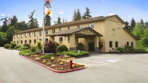 A two-story building with a beige exterior, a flagpole with an American flag, and a parking lot with marked spaces.