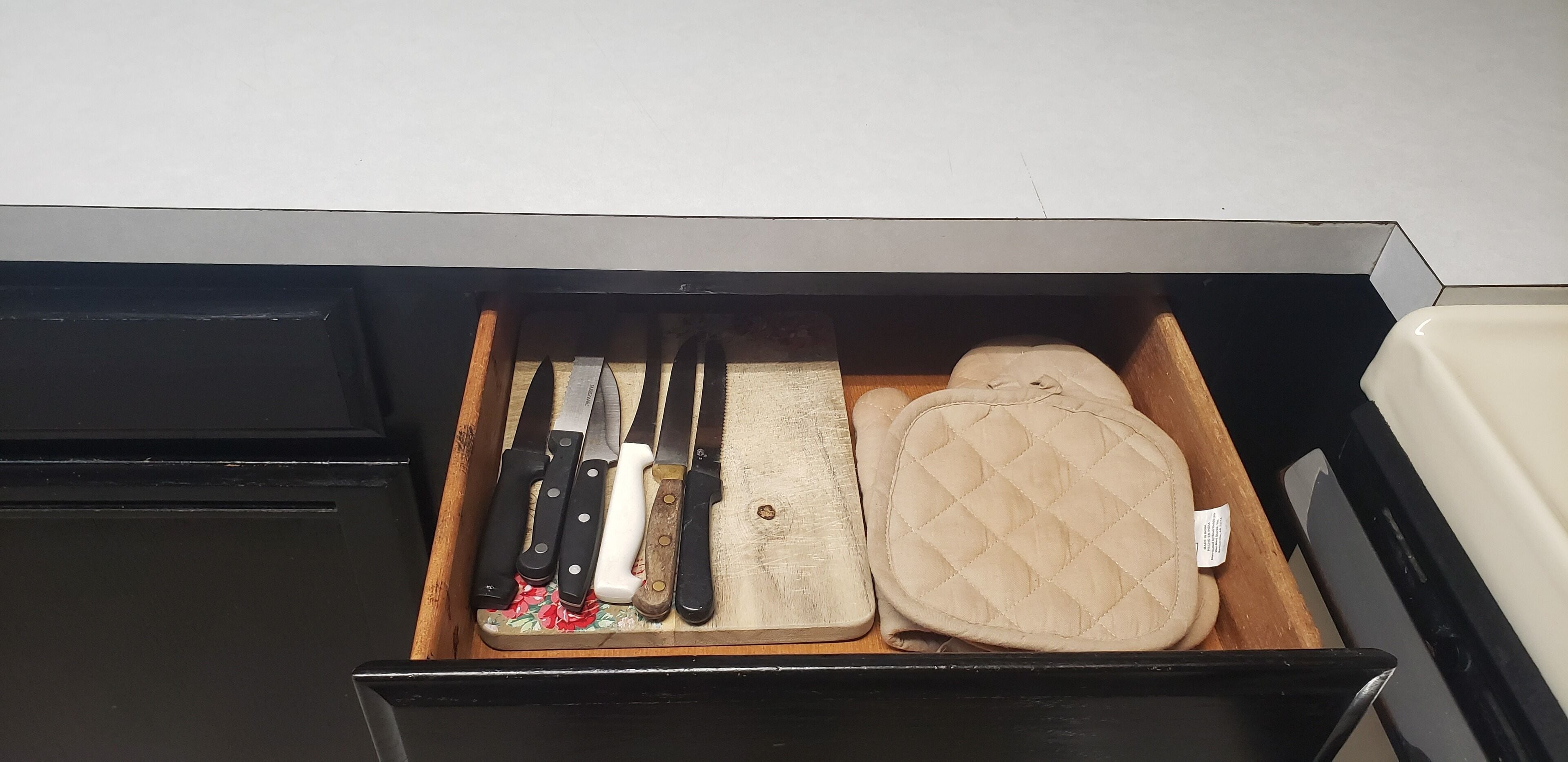 Un tiroir contenant divers ustensiles de cuisine et une planche à découper.
