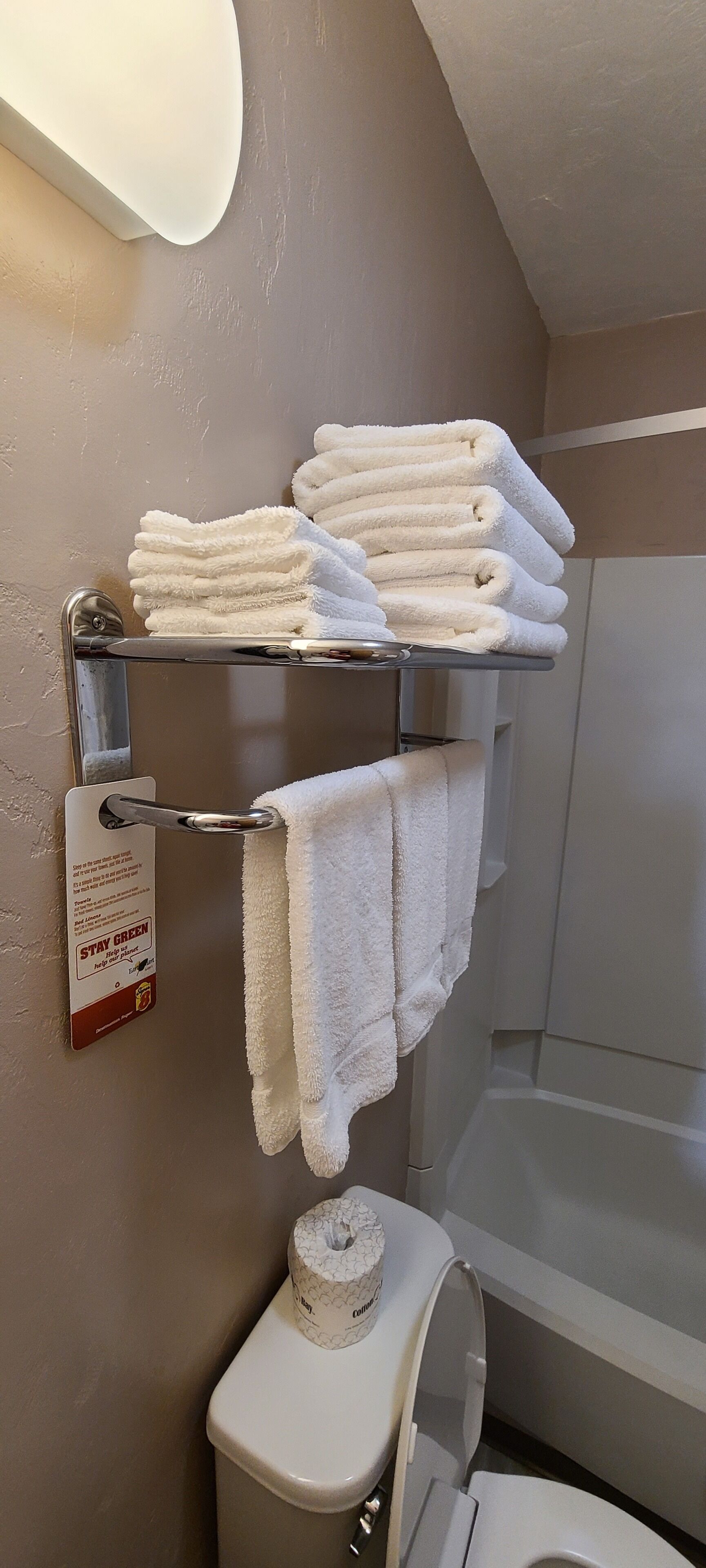 Kylpyhuone, jossa on wc, hyllyllä pino valkoisia pyyhkeitä ja wc-paperirulla.