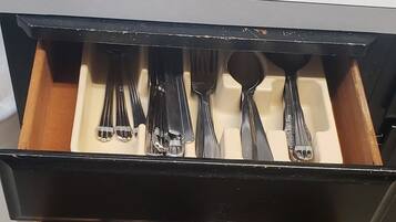 A drawer with utensils including forks, spoons, and knives.