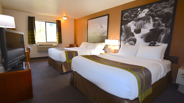 A hotel room with two beds, a television, a large window with curtains, and a waterfall painting on the wall.