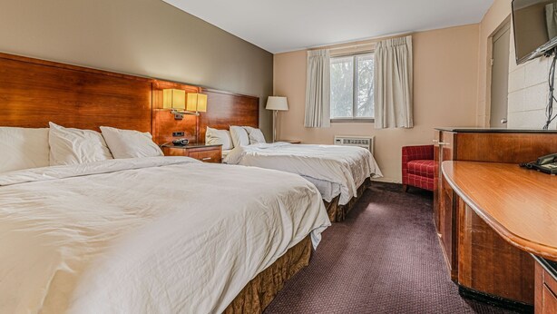 Quarto de hotel com duas camas, uma escrivaninha, uma cadeira e uma televisão.