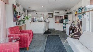Quarto de hotel compacto com cozinha compacta, pequena área de refeições e sala de estar com um sofá vermelho e um sofá branco.