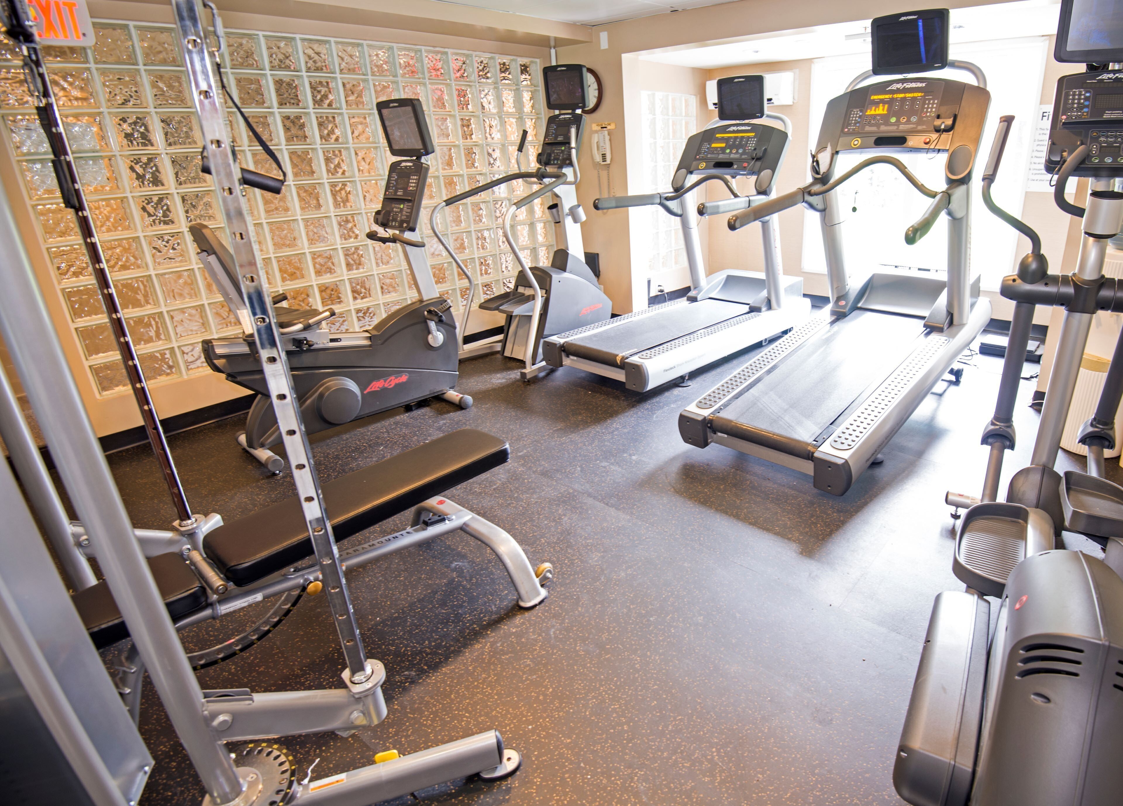 Une salle de sport équipée de tapis de course, de vélos elliptiques et d'appareils de musculation.