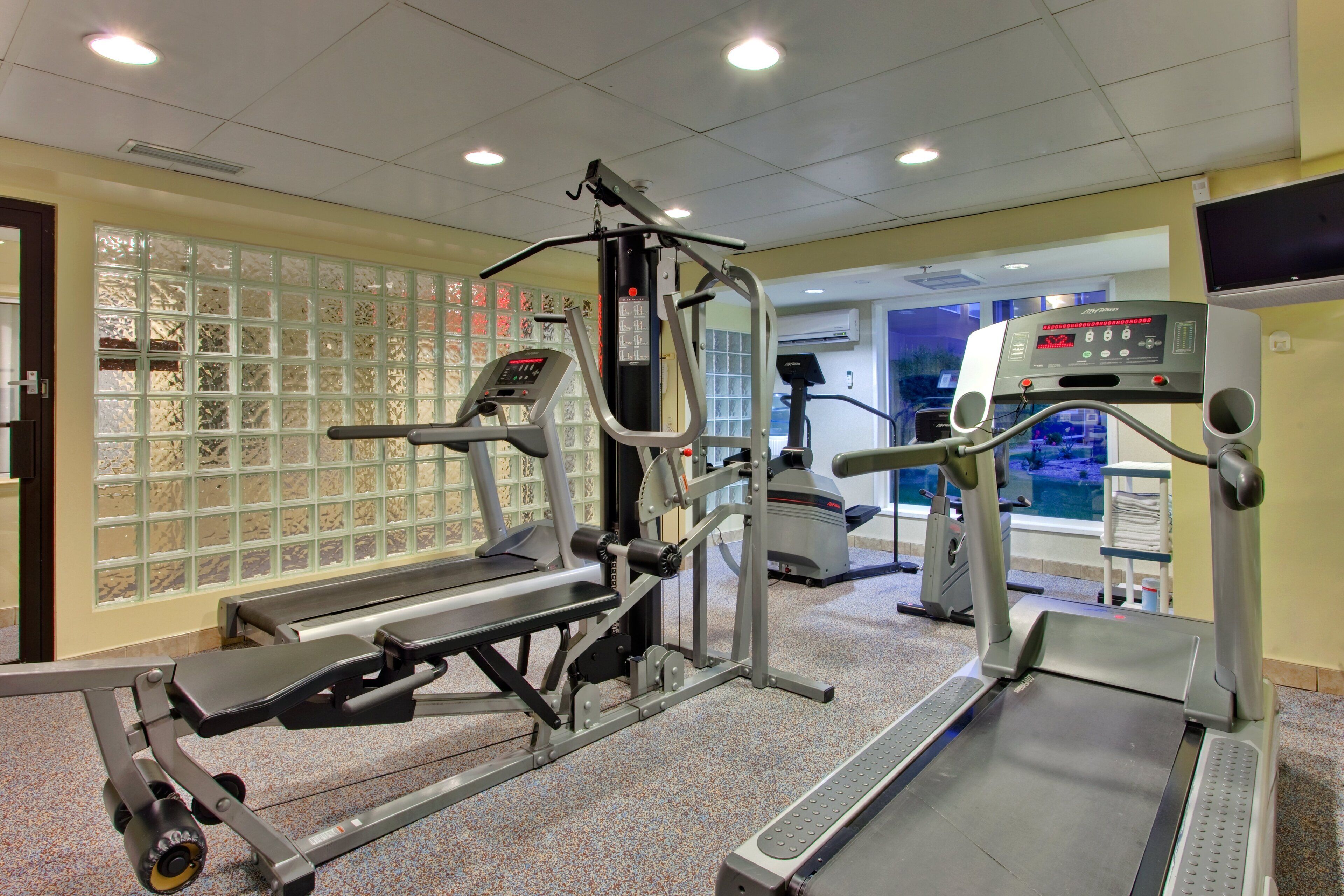 Une salle de sport équipée de divers appareils d’exercice, notamment des tapis de course et des appareils de musculation.