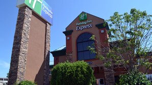 A Holiday Inn Express building with a prominent sign, stone pillars, and a clear blue sky.