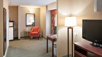 A hotel room with a television, a desk, a chair, a lamp, and a mirror.
