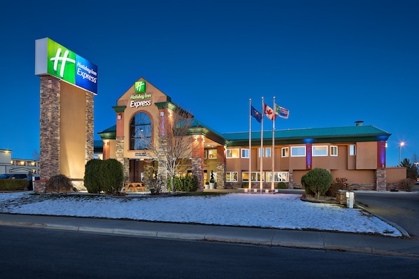 A Holiday Inn Express hotel with a stone facade, a prominent entrance, and flags.